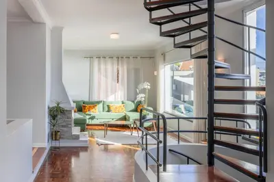 a living room with a green couch and a spiral staircase at SUNSET VILLA in Caniço