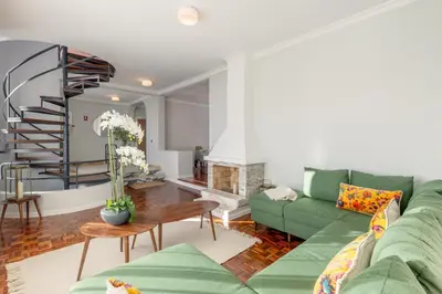 a living room with a green couch and a spiral staircase at SUNSET VILLA in Caniço