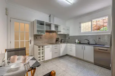 a kitchen with white cabinets and a table at SUNSET VILLA in Caniço