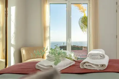 a room with a bed with towels and a window at SUNSET VILLA in Caniço