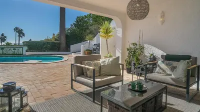a patio with two chairs and a table and a pool at Casa das Palmeiras, Luxury Villa in Luz