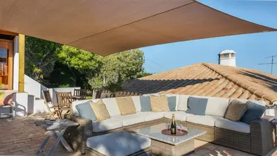 a couch under a large umbrella on a patio at Casa das Palmeiras, Luxury Villa in Luz