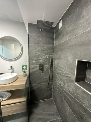 a bathroom with a shower with a sink and a mirror at The Green Valley House in São Vicente
