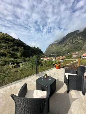 a patio with chairs and tables and a view of mountains at The Green Valley House in São Vicente