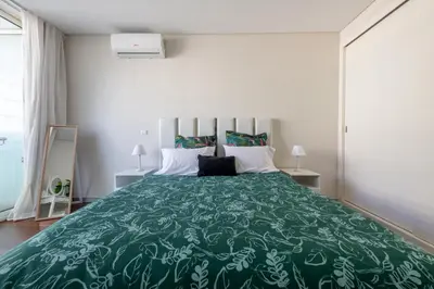 a bedroom with a large bed with a green bedspread at Funchal Plaza in Funchal