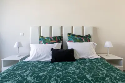 a bedroom with a large green bed with two lamps at Funchal Plaza in Funchal