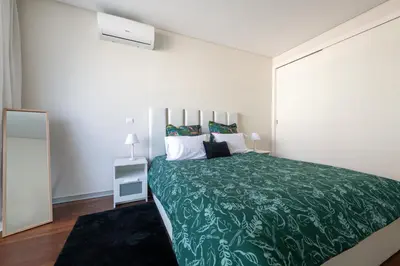 a bedroom with a large bed with a green blanket at Funchal Plaza in Funchal