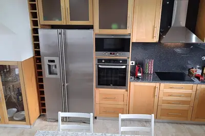 a kitchen with a stainless steel refrigerator and wooden cabinets at Casa Monte Ponta do Sol SeaViews in Ponta do Sol