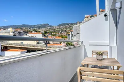 a balcony with a wooden table and a view of a city at Beco Santa Emilia 4O, a Home in Madeira in Funchal