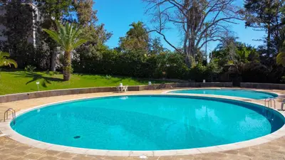 a large swimming pool in a yard with trees at Caracas Escape by LovelyStay in Funchal