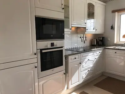 a white kitchen with white cabinets and black appliances at Casa com Vista in Lagos