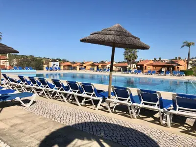 a row of chairs and an umbrella next to a swimming pool at Casa com Vista in Lagos