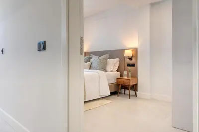 a white bedroom with a bed and a table at Beco Santa Emilia 4P, a Home in Madeira in Funchal