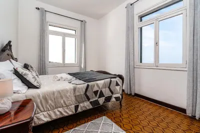 a bedroom with a bed and two windows at Achada House - Traditional House in Calheta