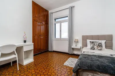 a bedroom with a bed and a desk and a window at Achada House - Traditional House in Calheta