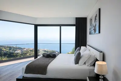 a bedroom with a large bed with a large window at Villa Panorâmica III in Arco da Calheta