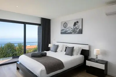 a bedroom with a large bed and a large window at Villa Panorâmica III in Arco da Calheta