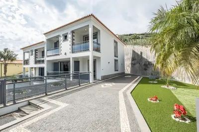a white house with a courtyard and palm trees at Til Home by Homie in Funchal