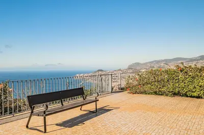 a bench sitting on a brick walkway near the ocean at THE OLD CHAPEL HOUSE in Funchal