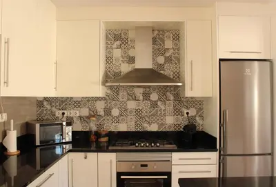 a kitchen with white cabinets and a stainless steel refrigerator at Canto do Vale in Aljezur