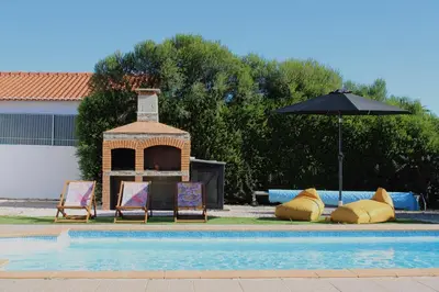 two chairs and an umbrella next to a swimming pool at Canto do Vale in Aljezur