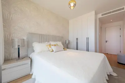 a white bedroom with a large white bed with gold pillows at The Queen Apartment By Sam Houses in Funchal