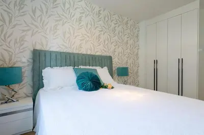 a bedroom with a white bed with a green headboard at The Queen Apartment By Sam Houses in Funchal
