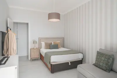 a white bedroom with a bed and a chair at Doca do Cavacas I by An Island Apart in Funchal