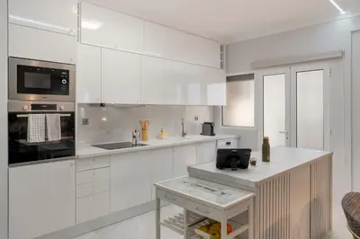 a white kitchen with white cabinets and a table at Doca do Cavacas I by An Island Apart in Funchal