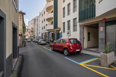 a red car parked in a parking lot on a city street at Casa da Cidade by An Island Apart in Funchal