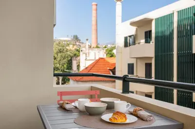 a table with cups and plates of food on a balcony at Casa da Cidade by An Island Apart in Funchal