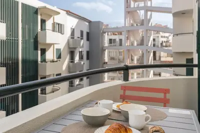 a table with cups and plates of food on a balcony at Casa da Cidade by An Island Apart in Funchal