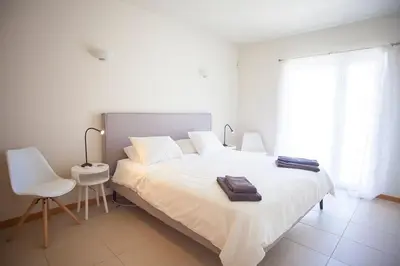 a white bedroom with a white bed and a chair at Casa Sol in Burgau