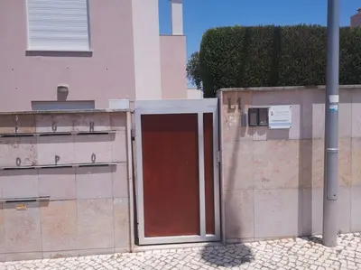 a building with a red door next to a wall at Casa Sol in Burgau