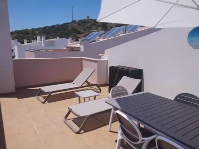a patio with a table and chairs on a roof at Casa Sol in Burgau