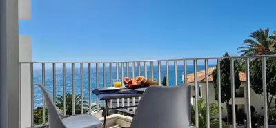 a balcony with a table and chairs and the ocean at Ponta Beachside by LovelyStay in Funchal