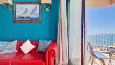 a red couch in a living room with a picture of a sail boat at Ponta Beachside by LovelyStay in Funchal
