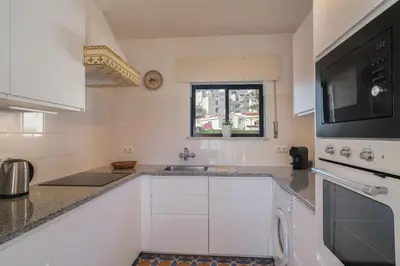 a white kitchen with a sink and a microwave at Casa da Praia in Luz