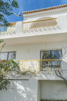 a white house with a yellow railing on a balcony at Casa da Praia in Luz
