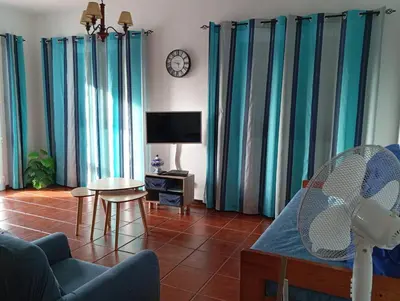 a living room with blue curtains and a tv at Sunrise Holidays in Porto Santo