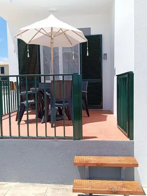 a patio with an umbrella and a table and a bench at Sunrise Holidays in Porto Santo