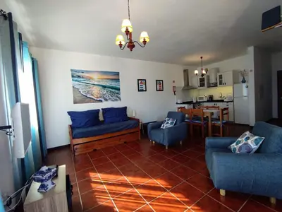 a living room with blue couches and a kitchen at Sunrise Holidays in Porto Santo