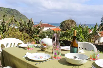 a small house with chairs and a mountain at Casa dos Magalhães in Vila do Porto