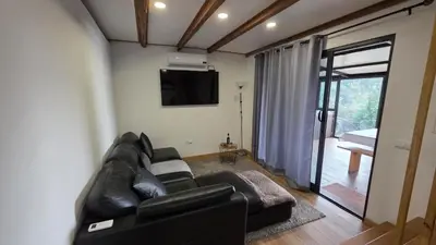 a living room with a black leather couch and a television at Casa Vicente in Arco da Calheta