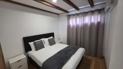a bedroom with a white bed and a curtain at Casa Vicente in Arco da Calheta