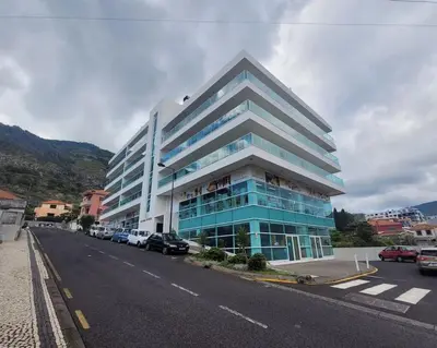 a large blue building with cars parked in front of it at Nova Madeira Apartment Machico in Machico