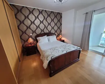 a bedroom with a bed and two night stands with lamps at Nova Madeira Apartment Machico in Machico