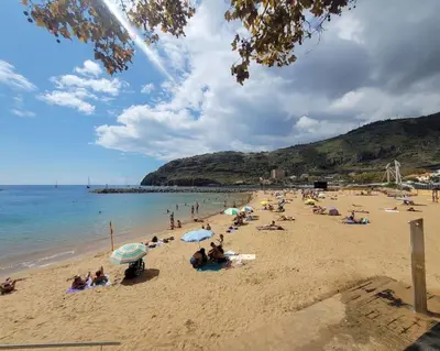 a group of people on a beach with umbrellas at Nova Madeira Apartment Machico in Machico