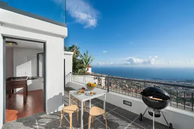 a balcony with a table and chairs and the ocean at OurMadeira - Monte White House in Funchal