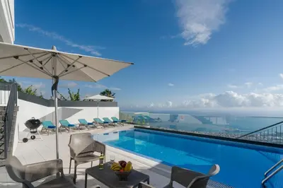 a swimming pool with chairs and an umbrella at OurMadeira - Monte White House in Funchal